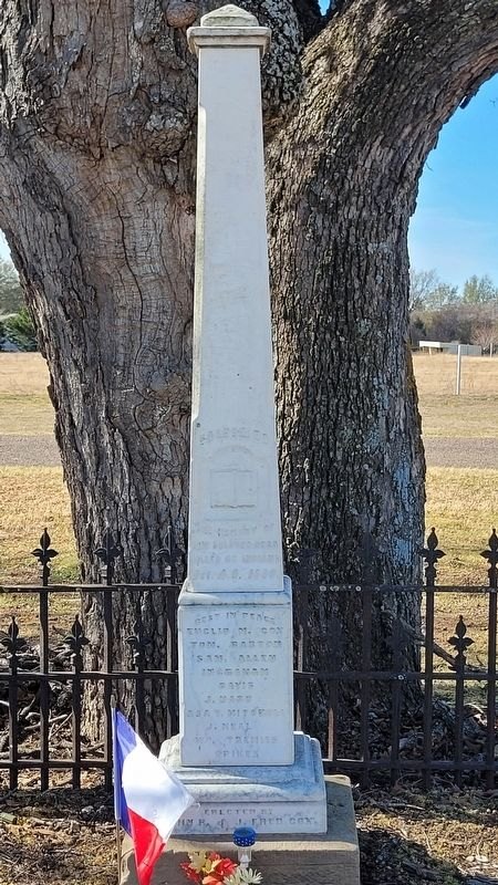 The marble shaft over the common grave, standing between two oak trunks grown together