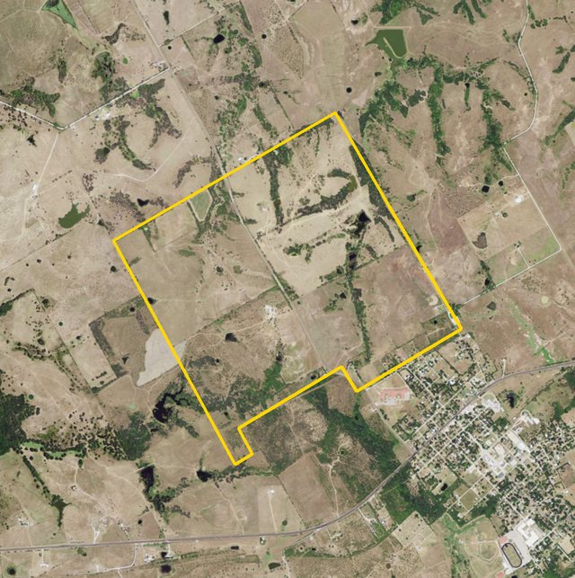An aerial photograph from 2012 of pasture, tree lines and stock ponds, the Cazneau survey outlined in yellow, Blooming Grove at its lower right