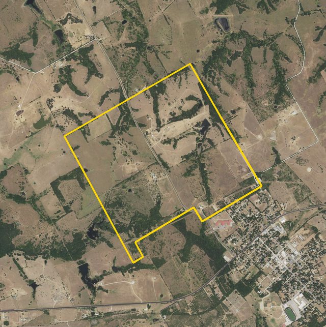 An aerial photograph from 2022 of pasture, tree lines and stock ponds, the Cazneau survey outlined in yellow, Blooming Grove at its lower right