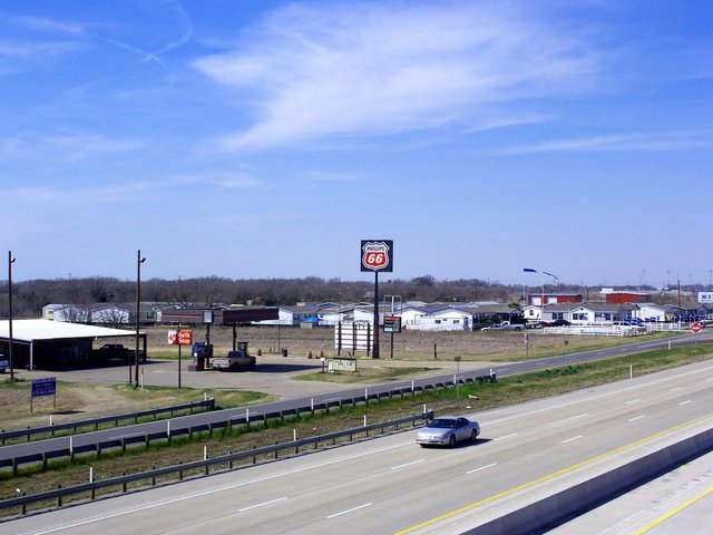 Interstate 45 seen from an overpass at Rice, a service road, a gas station and rows of houses beyond