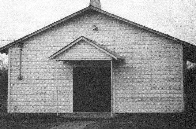 A small square white frame church with a gabled porch over the door